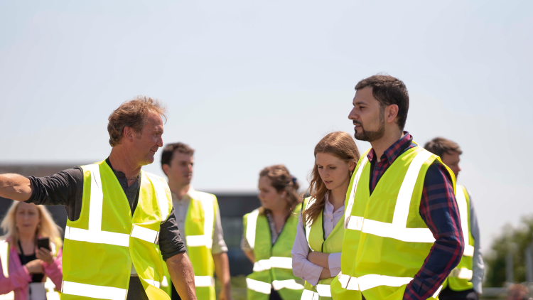 on the roof of the Royal Northern College of Music standing next to roof top solar panels., people walking in high visibility jackets together